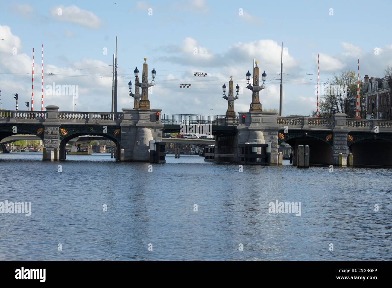 Pont historique Hogesluis à Amsterdam, pays-Bas. La pierre voûtée enjambe un canal bordé de péniches, symbole de la riche histoire et de la fin de la ville Banque D'Images