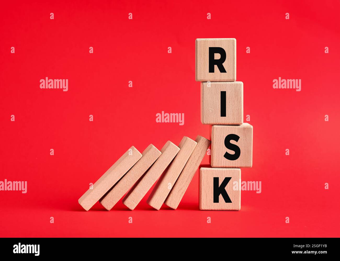 Effet domino et concept de gestion des risques. Prise de risque en entreprise. Les dominos en bois démolissent les cubes avec le mot risque. Banque D'Images