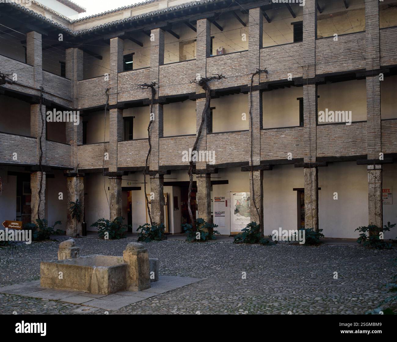 Courtyard, Corral del Carbon, Grenade, Andalousie, Espagne (2002). L'un des bâtiments les plus importants préservés de la période nasride de Grenade, à l'origine al-Funduq al-Jadida, a eu de nombreuses utilisations tout au long de son histoire. Construit au XIVe siècle au milieu de la zone commerciale. Après 1531, il a été appelé Corral del Carbon en raison de son utilisation comme stockage pour le charbon. Il devint plus tard une cour théâtrale (un corral de comedias). À partir du XVIIe siècle, il a été transformé en petits appartements avec une cour centrale. À l'heure actuelle, il est utilisé comme centre culturel. Banque D'Images