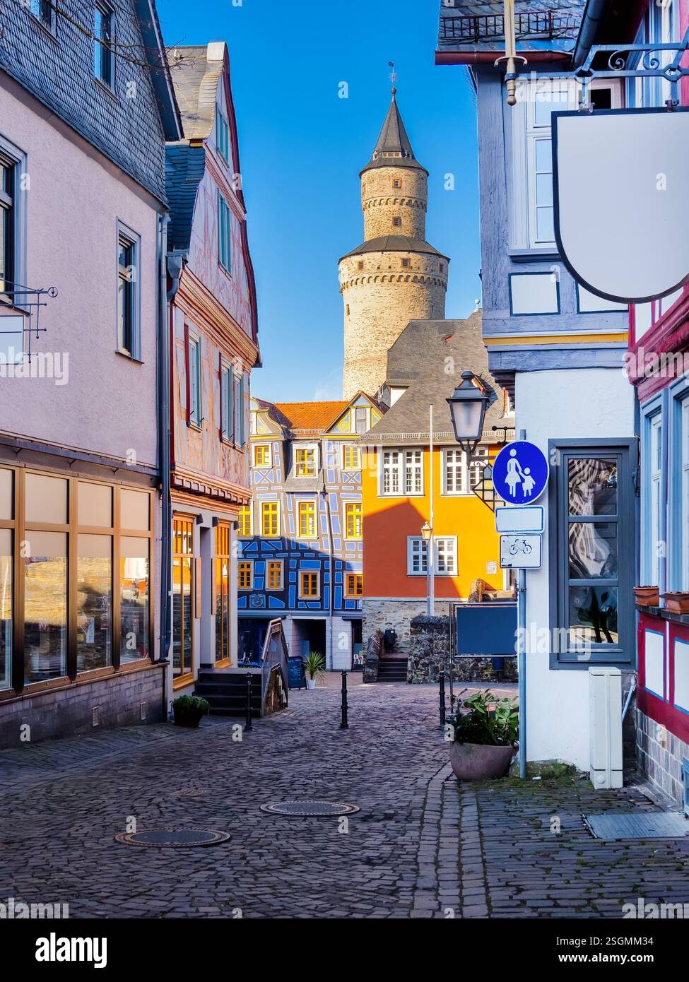 Charmante ruelle pavée présentant des maisons à colombages colorées et l'historique hexenturm sous un ciel bleu clair à Idstein, en allemagne Banque D'Images