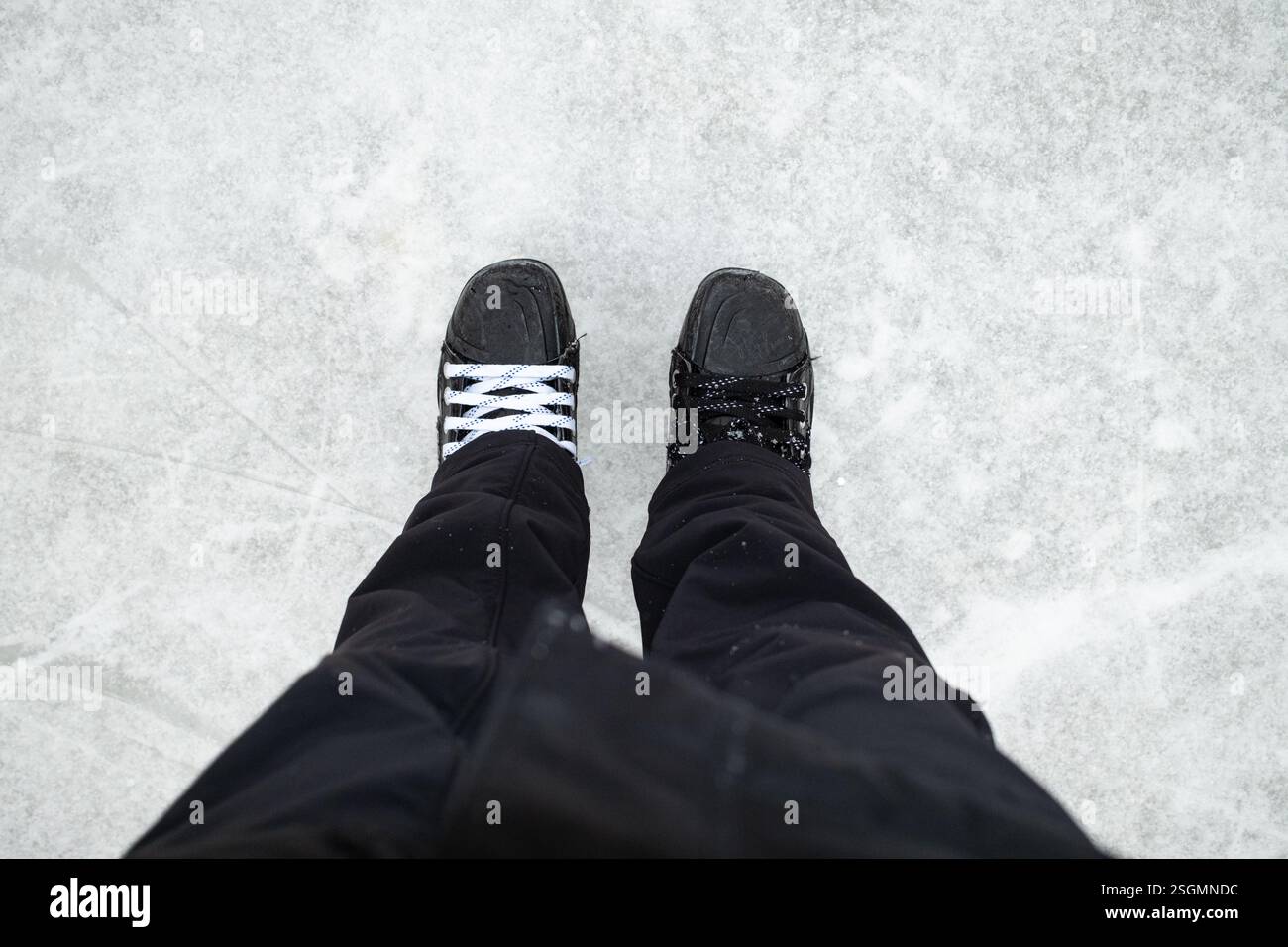 Gros plan de patins à glace avec lacets mal assortis sur une surface de patinoire. Banque D'Images