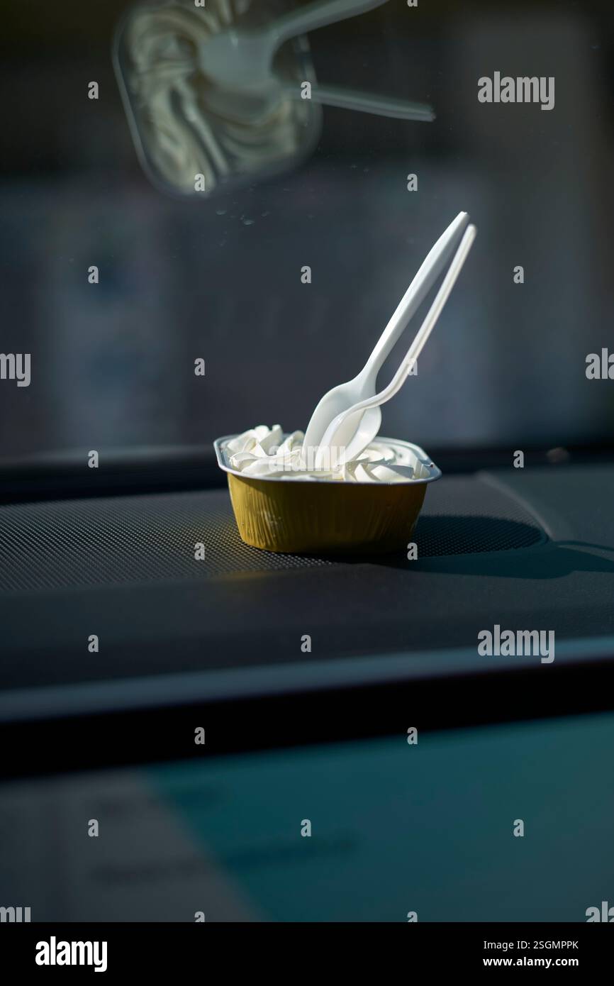 Tasse à pâtisserie avec cuillères en plastique sur le tableau de bord d'une voiture à la lumière du soleil, Florida Keys, USA Banque D'Images
