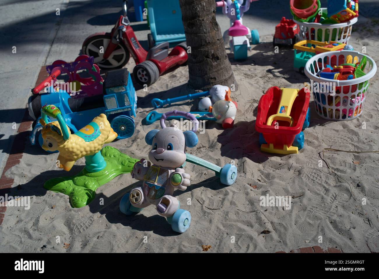 Jouets pour enfants dispersés sur un sol sablonneux à la lumière du soleil sur une aire de jeux., Miami, Floride, États-Unis Banque D'Images