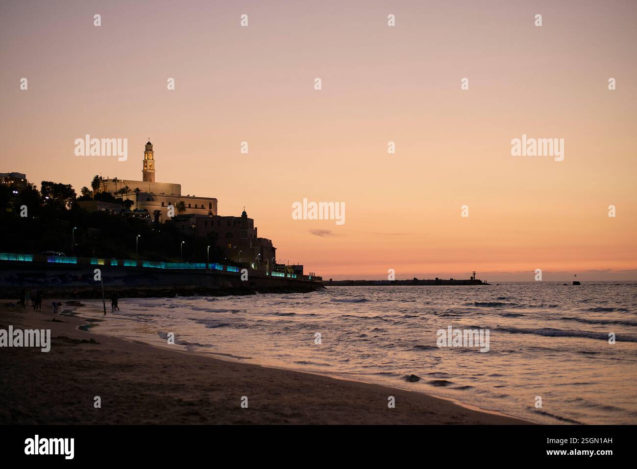 Paysage urbain côtier au crépuscule avec une silhouette de phare proéminente contre un ciel coloré, Israël Banque D'Images