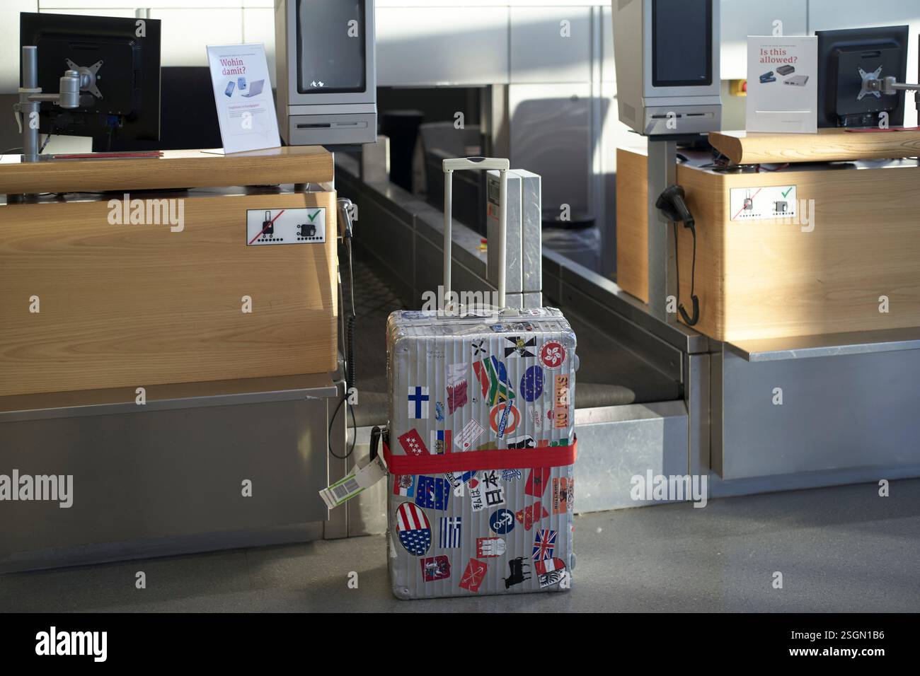 Valise recouverte d'autocollants internationaux par un comptoir d'enregistrement à l'aéroport Banque D'Images