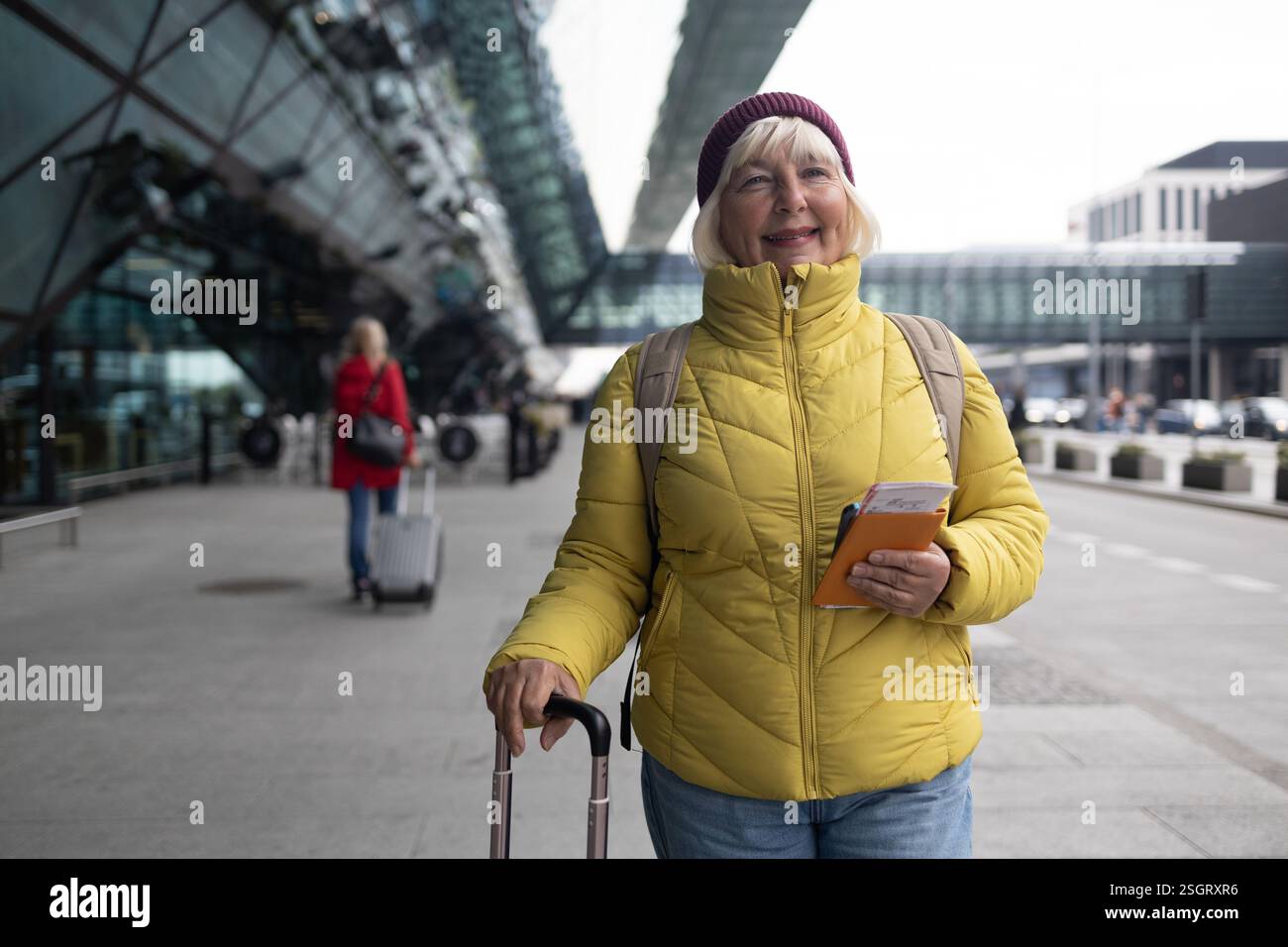 Jeune voyageuse femme marchant avec une valise bleue à l'arrêt de transport moderne à l'extérieur. Concept de transport urbain et de voyage Banque D'Images
