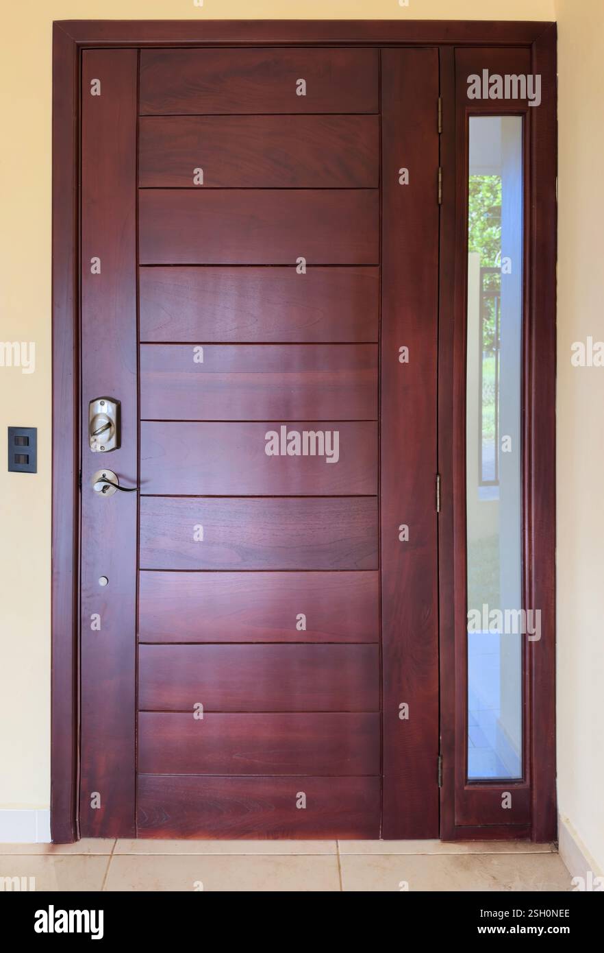 La porte en bois magnifiquement conçue dispose d'un design élégant avec panneau de verre, améliorant l'esthétique moderne de l'entrée. Banque D'Images
