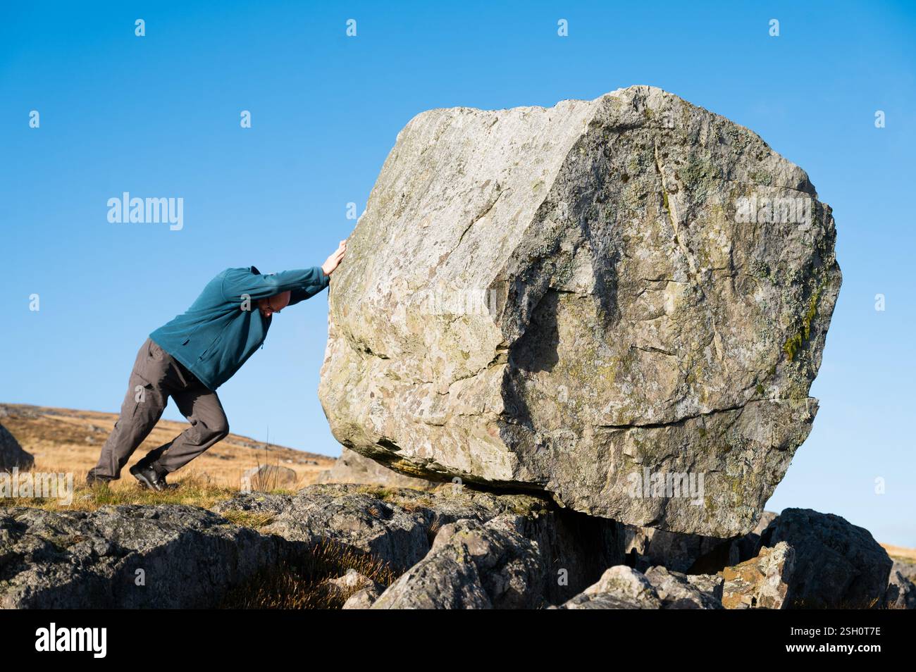 Homme essayant de pousser le rocher sur Cefn Carn Fadog, Mynydd du, Bannau Brycheiniog, pays de Galles, Royaume-Uni Banque D'Images