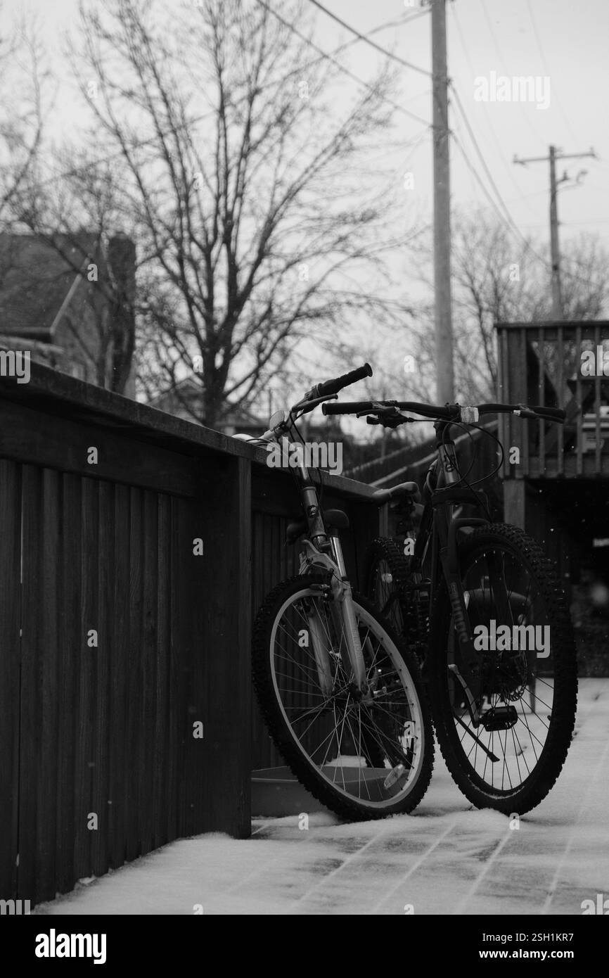 Bicyclettes reposant sur une balustrade en bois saupoudrée de neige dans la scène hivernale Banque D'Images