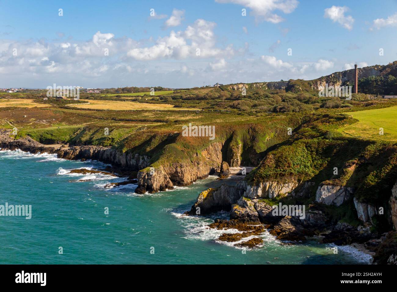 Le littoral et les falaises accidentées à Porth Namarch avec Holyhead visible en arrière-plan sur la côte nord d'Anglesey dans le nord du pays de Galles au Royaume-Uni Banque D'Images