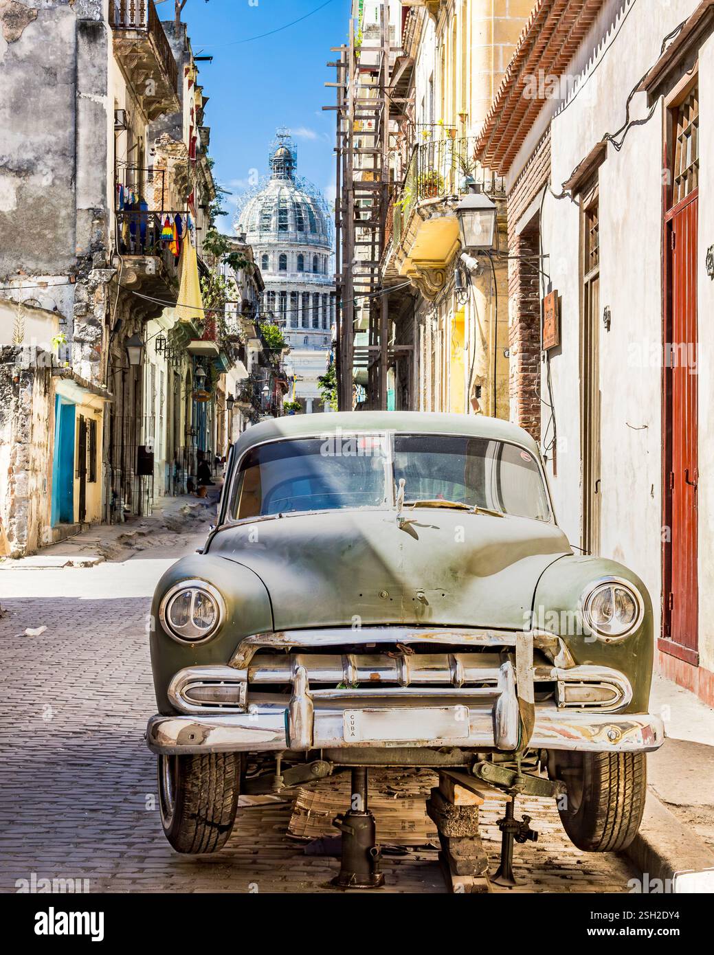 Vieille voiture en réparation dans les rues de la vieille Havane avec Capitolio en arrière-plan Banque D'Images