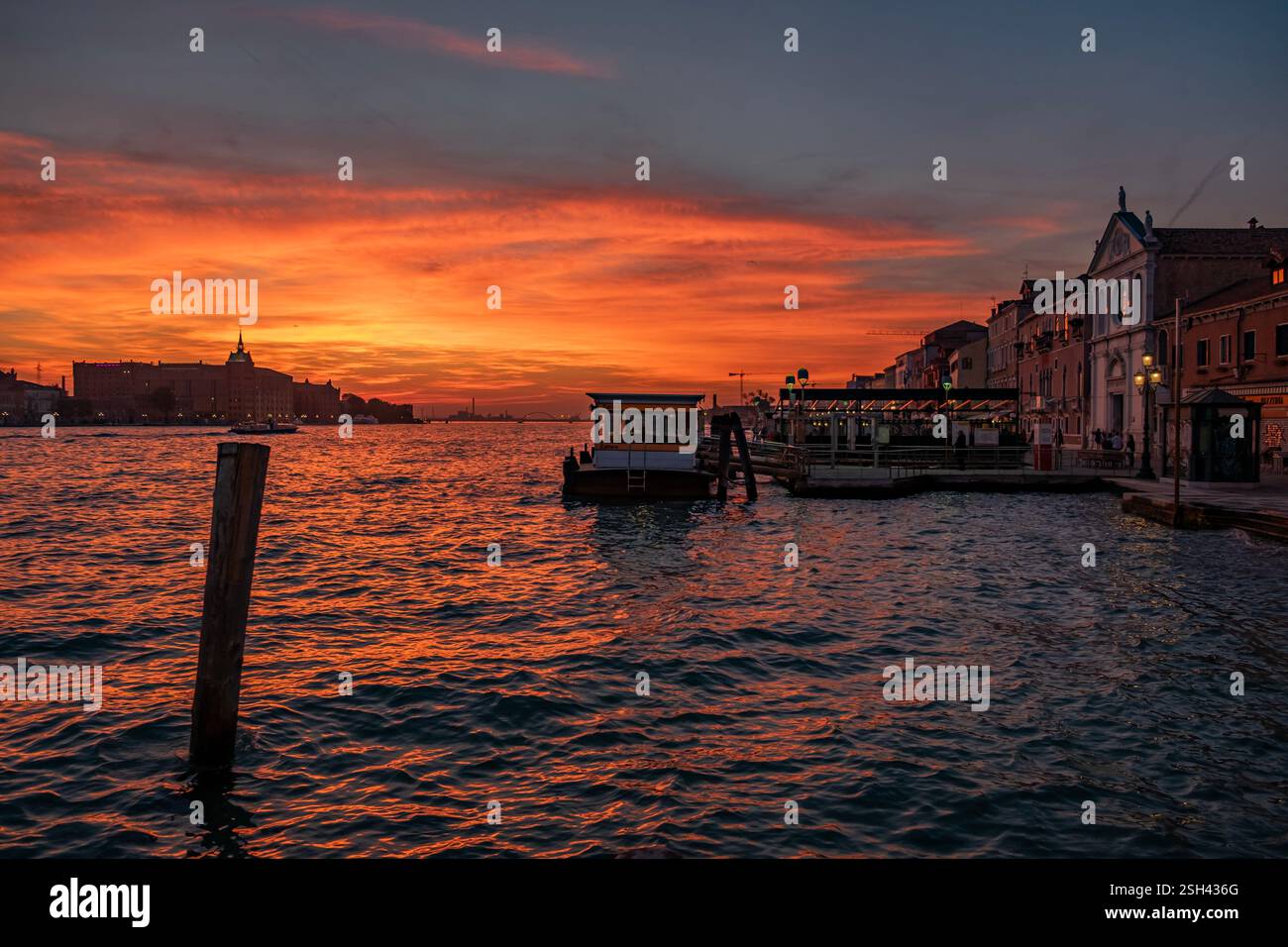 Sang rouge ciel coucher soleil sur la lagune de Venise avec Salute Basilique dômes et vieilles lampes Banque D'Images