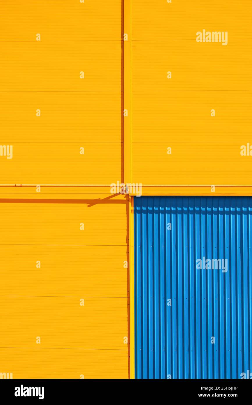 Détail d'un bâtiment d'entrepôt industriel avec des murs jaunes et une porte bleue comme fond minimaliste abstrait Banque D'Images