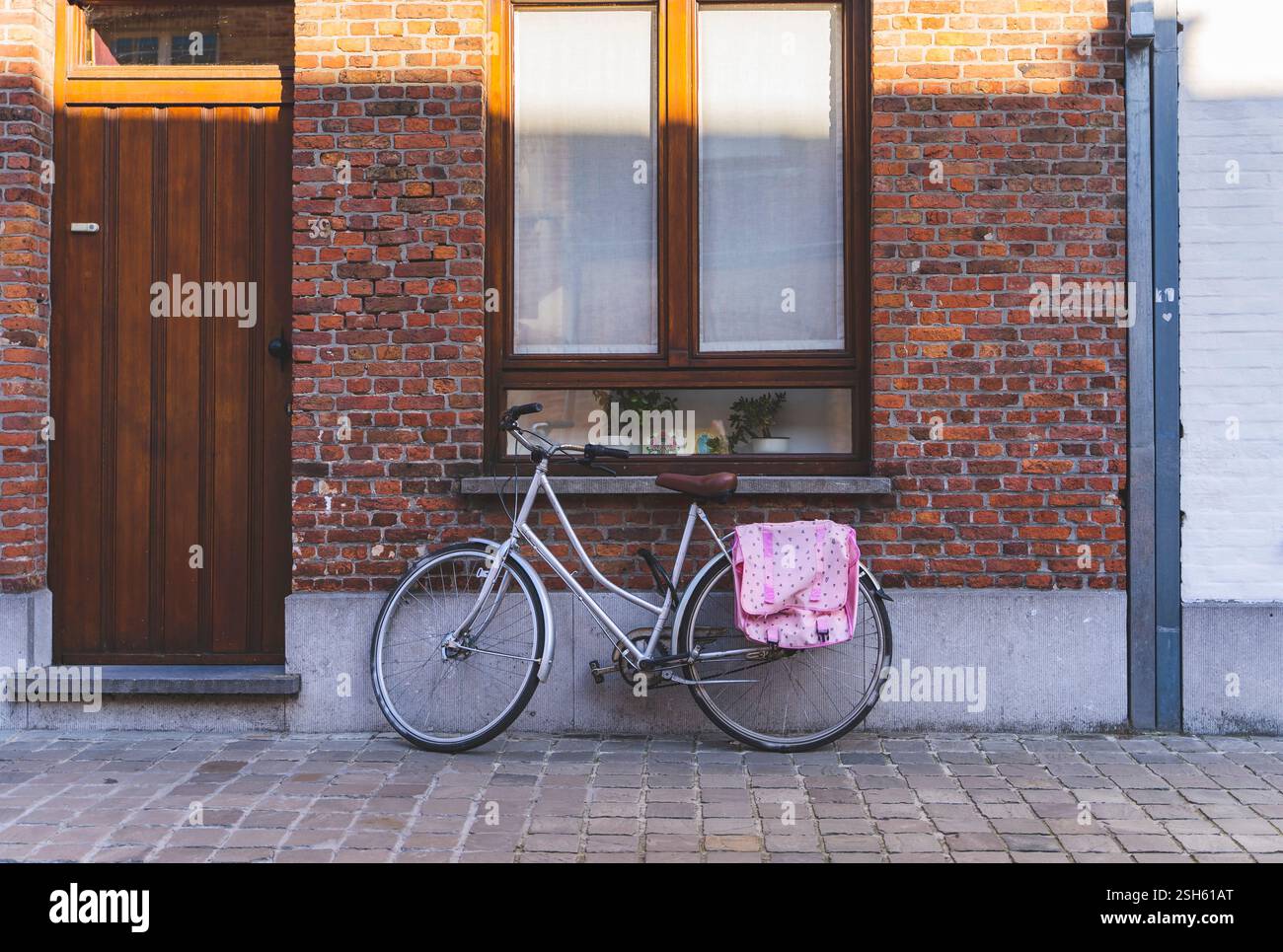 Vélo vintage appuyé contre le mur de briques avec fenêtre. Banque D'Images