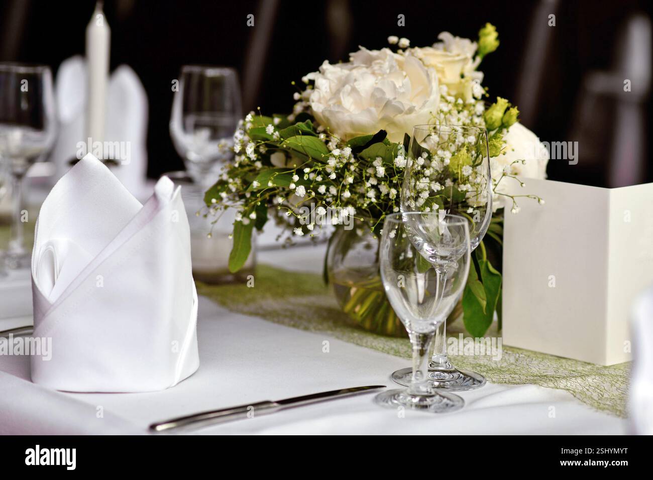 Beaux bouquets de fleurs blanches avec verres à boire et serviette en tissu à table de mariage Banque D'Images