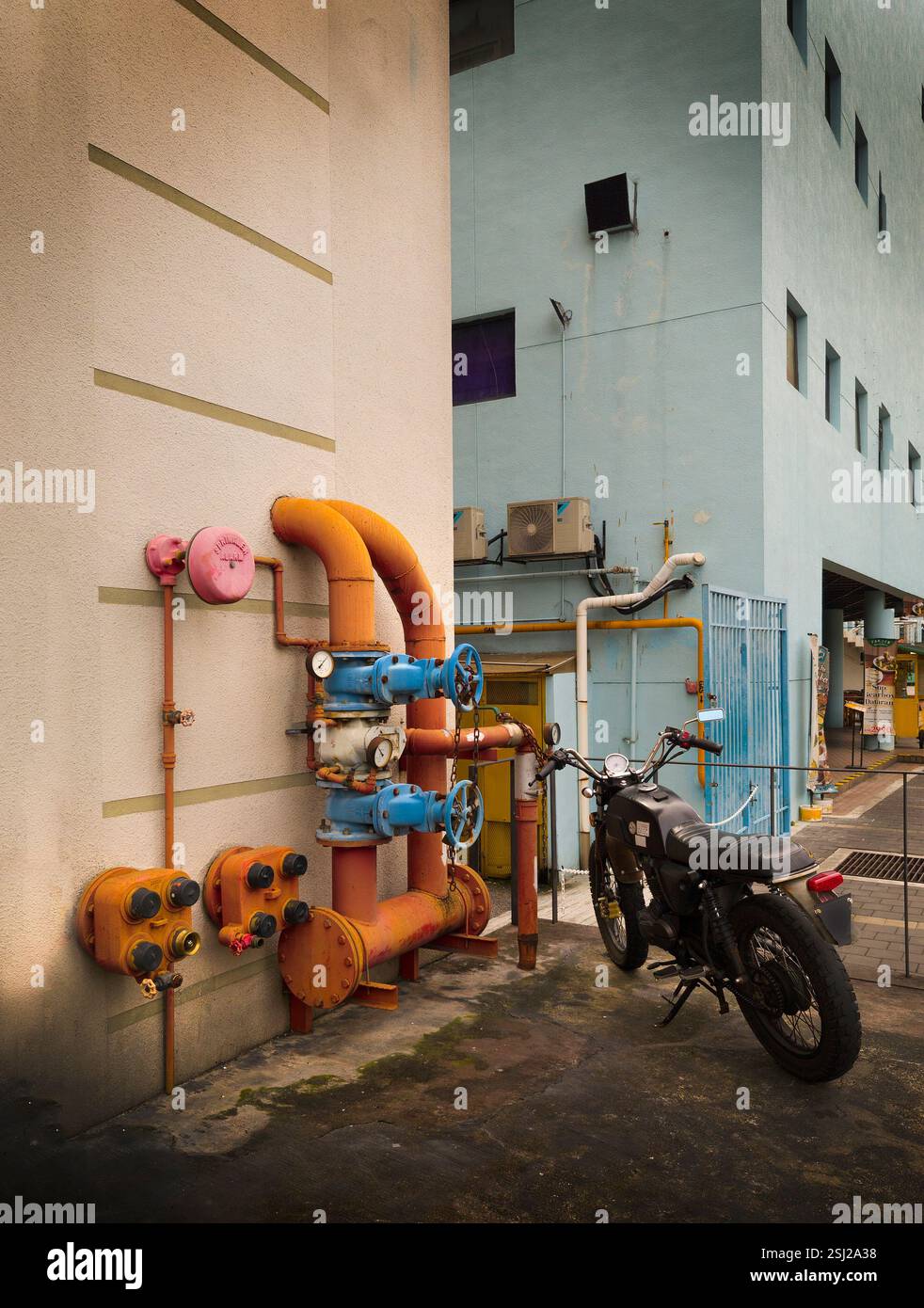 Tuyauterie industrielle colorée avec une moto vintage, Malaisie Banque D'Images