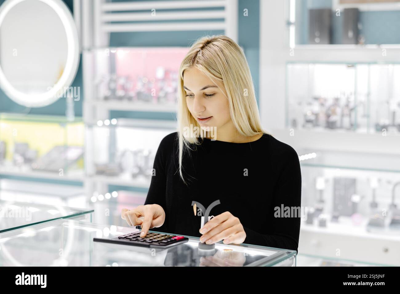 Vendeur de magasin de bijoux calculant le prix de l'or ou du diamant à l'aide de la calculatrice dans le magasin de bijoux Banque D'Images