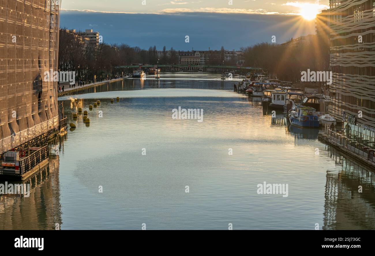 Paris, France - 02 01 2025 : vue sur le bassin de la Villette, les bateaux et la rotonde de Stalingrad depuis la passerelle au coucher du soleil Banque D'Images