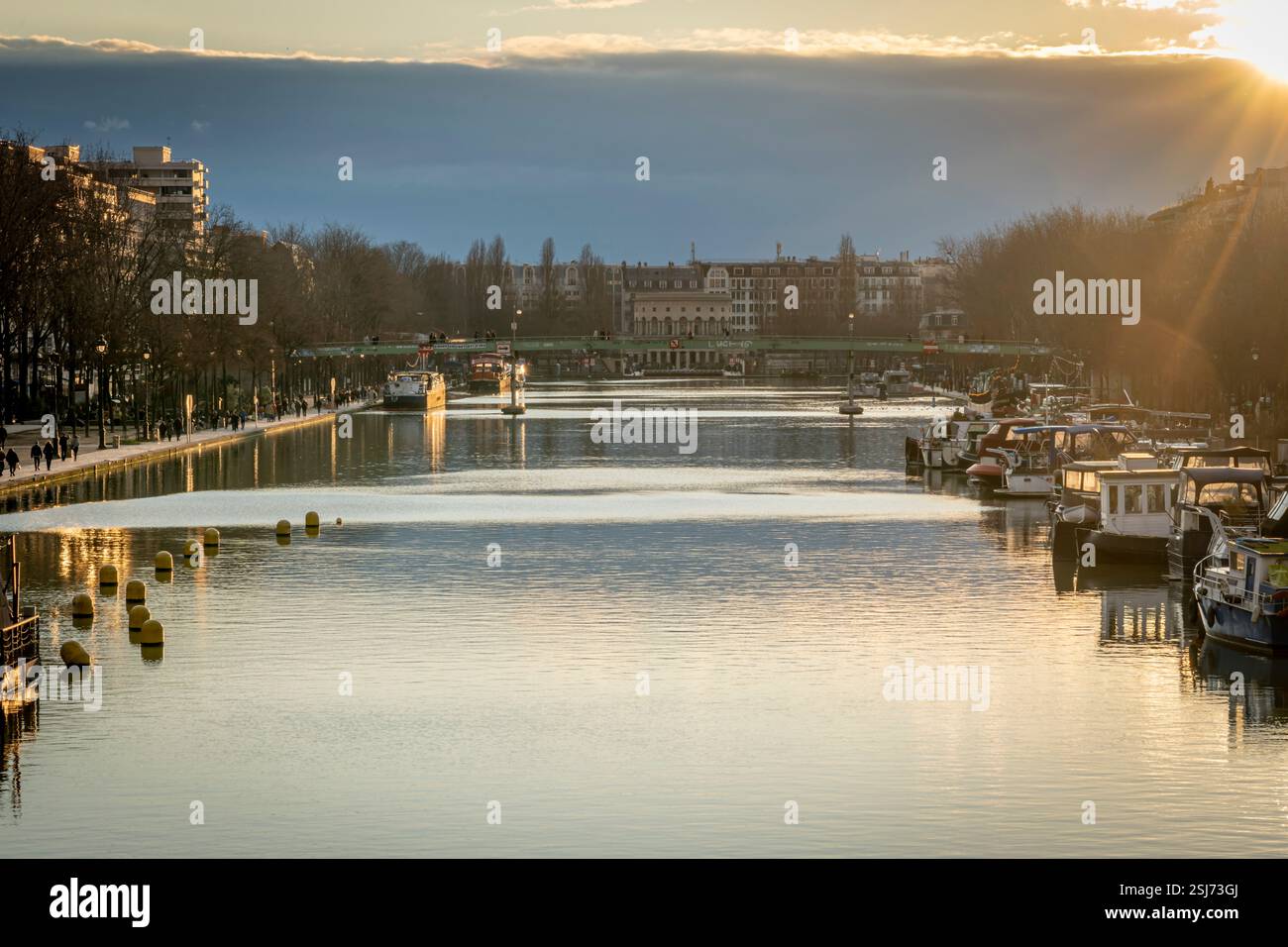 Paris, France - 02 01 2025 : vue sur le bassin de la Villette, les bateaux et la rotonde de Stalingrad depuis la passerelle au coucher du soleil Banque D'Images