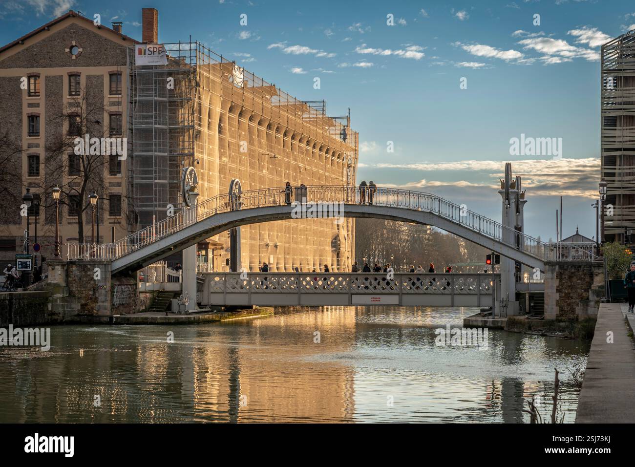 Paris, France - 02 01 2025 : vue sur le bassin de la Villette, le pont levant de Flandre et la passerelle au coucher du soleil Banque D'Images