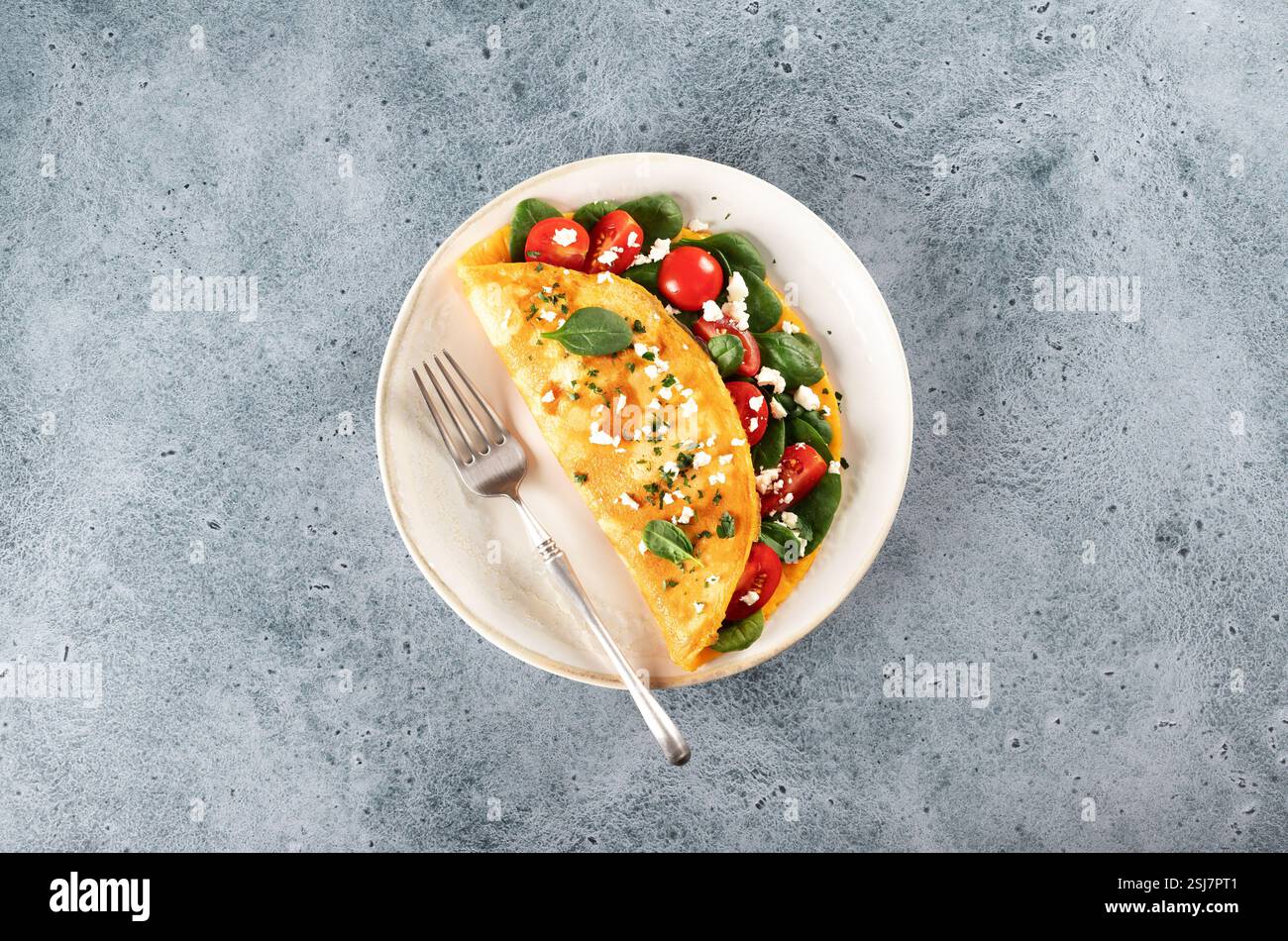 Omelette farcie aux tomates, fromage et épinards sur fond bleu. Vue de dessus. Copier l'espace. Banque D'Images