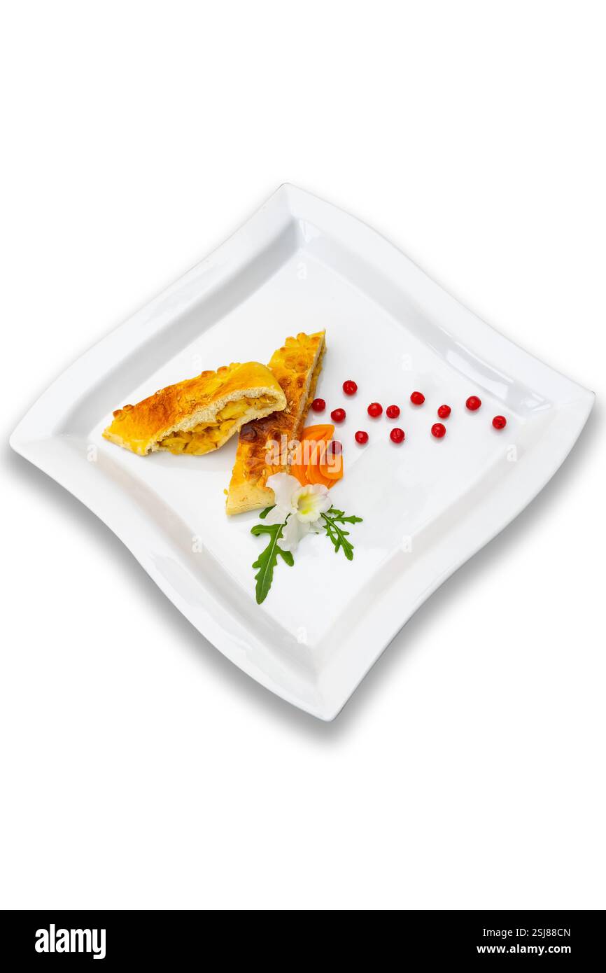 Un plat gastronomique magnifiquement plaqué présente une croûte dorée remplie d'ingrédients salés. Les garnitures fraîches ajoutent de la couleur, améliorant l'aspect visuel Banque D'Images