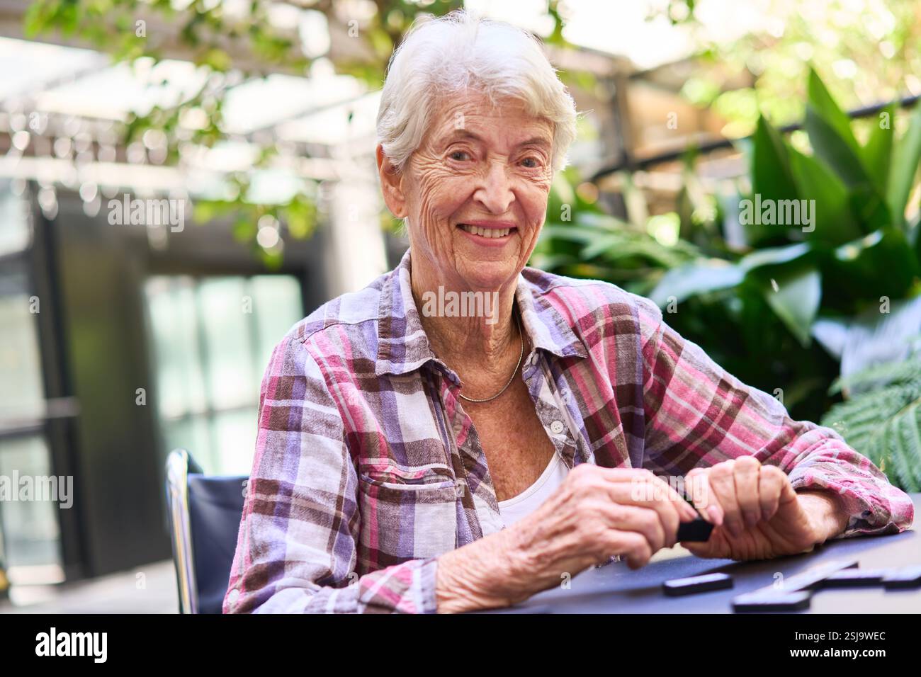 Une femme âgée sourit chaleureusement tout en participant à un jeu en plein air, entourée de verdure. Elle apparaît heureuse et contente dans un environnement social et serein Banque D'Images