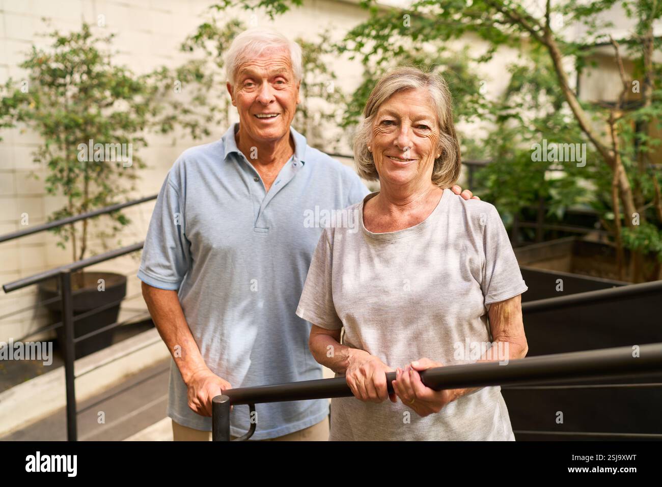 Homme et femme âgés souriant chaleureusement tout en profitant de leur temps dans un environnement extérieur verdoyant, mettant en valeur la chaleur et la compagnie. Banque D'Images