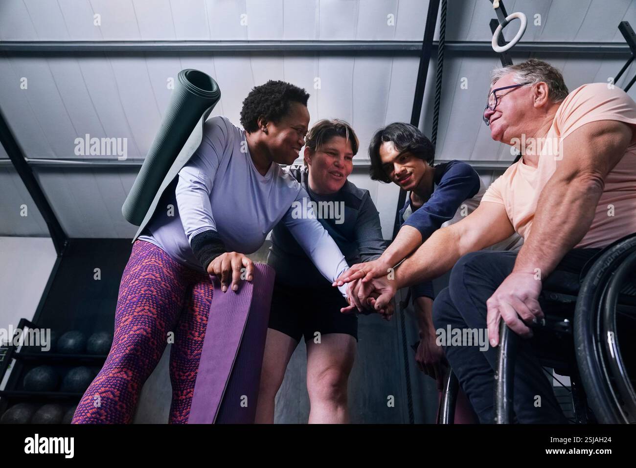Amis empilant les mains dans le studio de yoga Banque D'Images