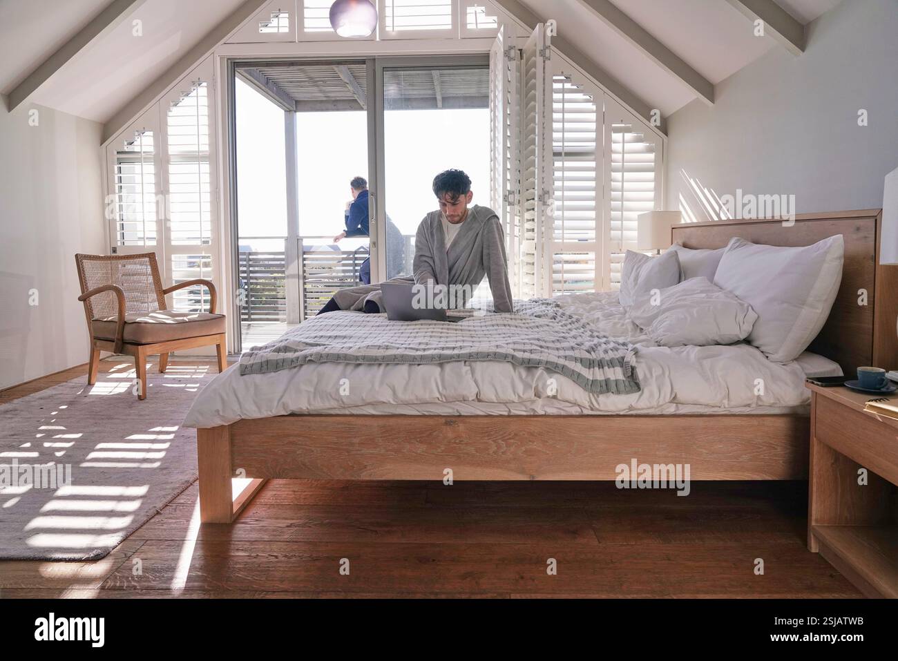 Man using laptop on bed Banque D'Images