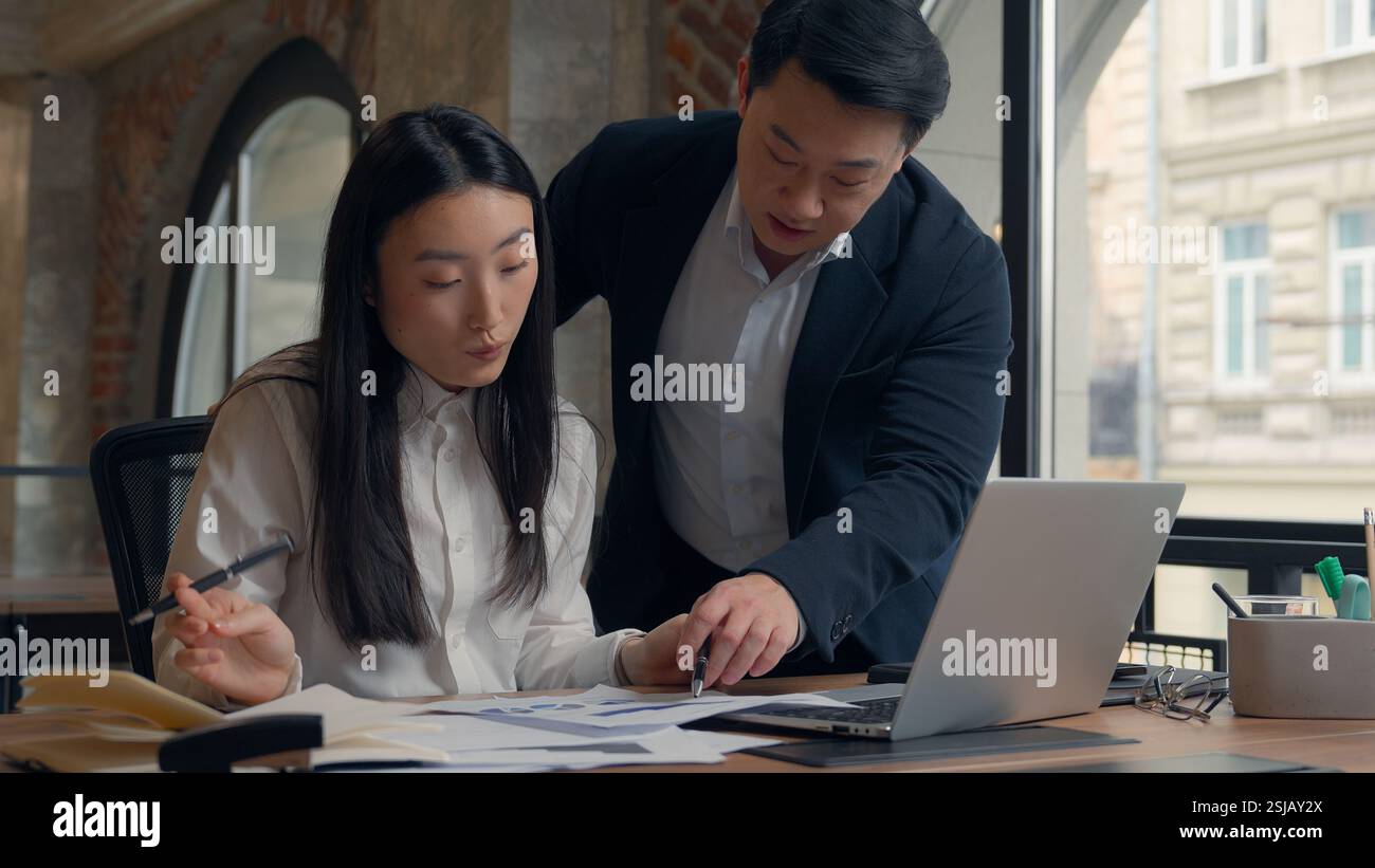 Deux directeurs d'entreprise collègues des collègues asiatiques travaillent ensemble des documents de travail d'équipe analysent la femme chinoise fille femme d'affaires japonaise homme coréen Banque D'Images