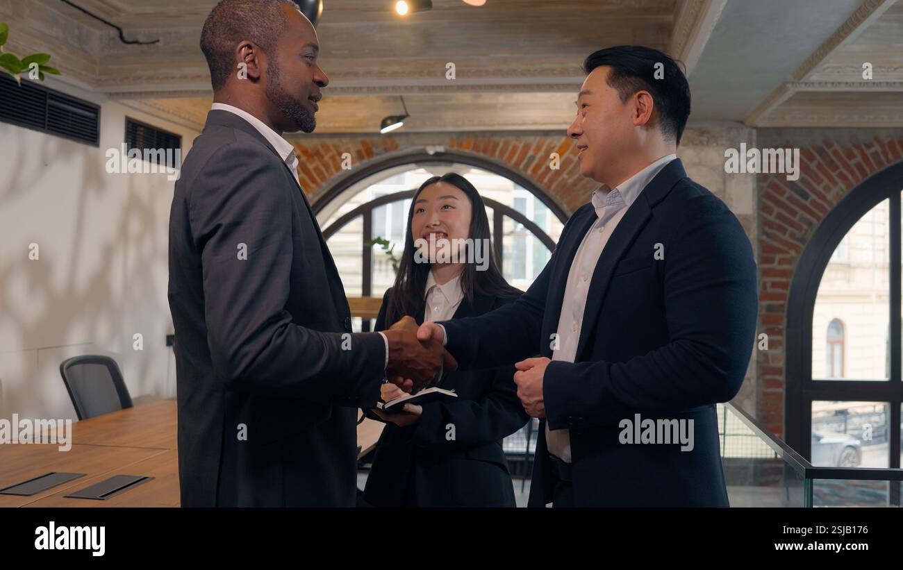 Trois personnes multiraciales d'affaires dans le bureau deux hommes d'affaires hommes d'affaires africains homme d'affaires asiatique Corée homme gars parlant poignée de main saluant succès deal Banque D'Images
