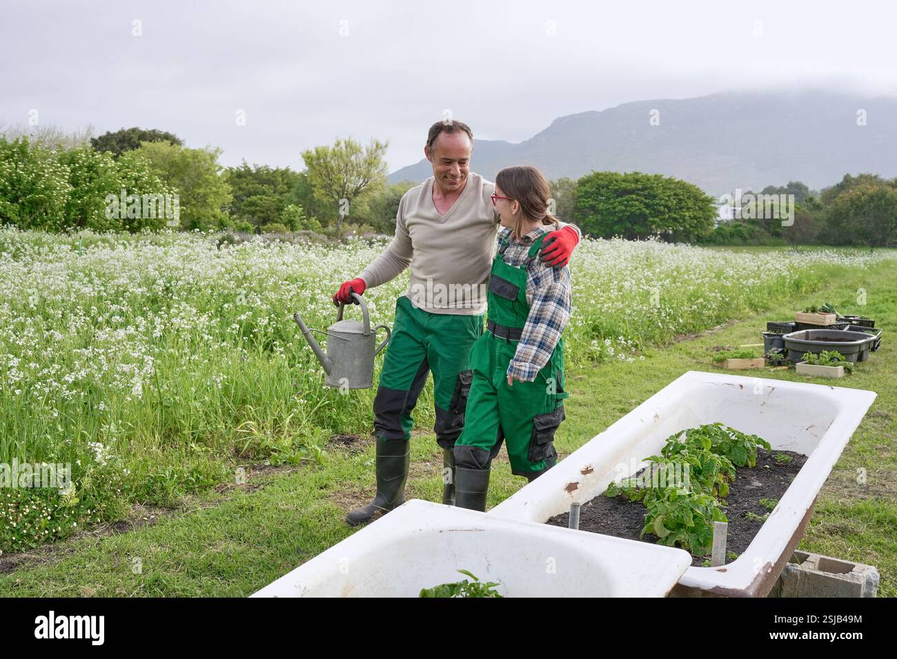 Agriculteurs embrassant et marchant le long des baignoires avec des légumes plantés Banque D'Images Agriculteurs embrassant et marchant le long des baignoires avec des légumes plantés Banque D'Images