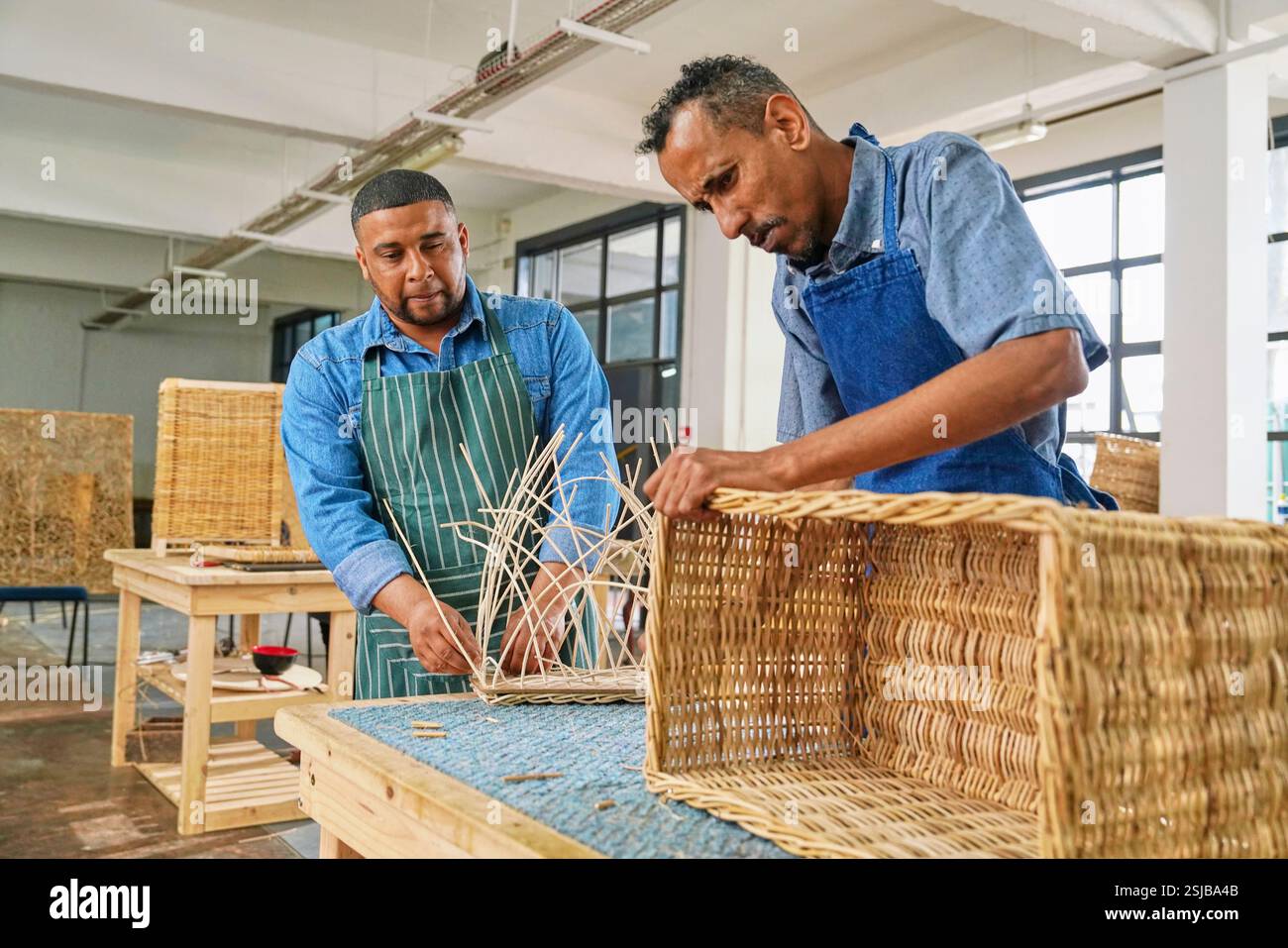 Deux artisans fabriquant des meubles tissés en atelier Banque D'Images