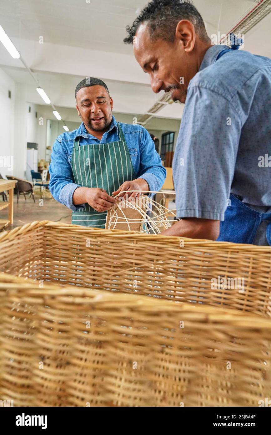 Deux artisans fabriquant des meubles tissés en atelier Banque D'Images