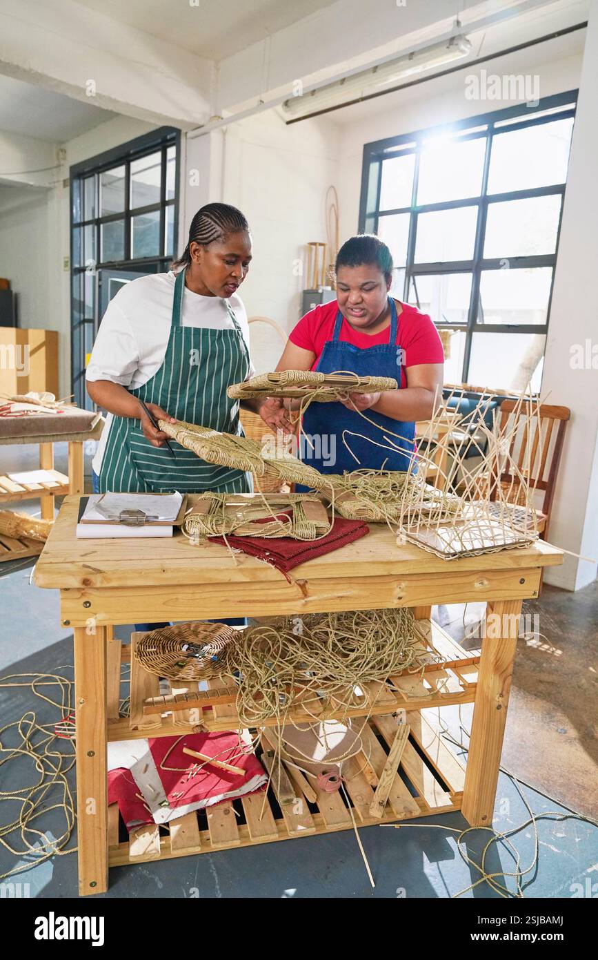 Deux artisans fabriquant des meubles tissés en atelier Banque D'Images