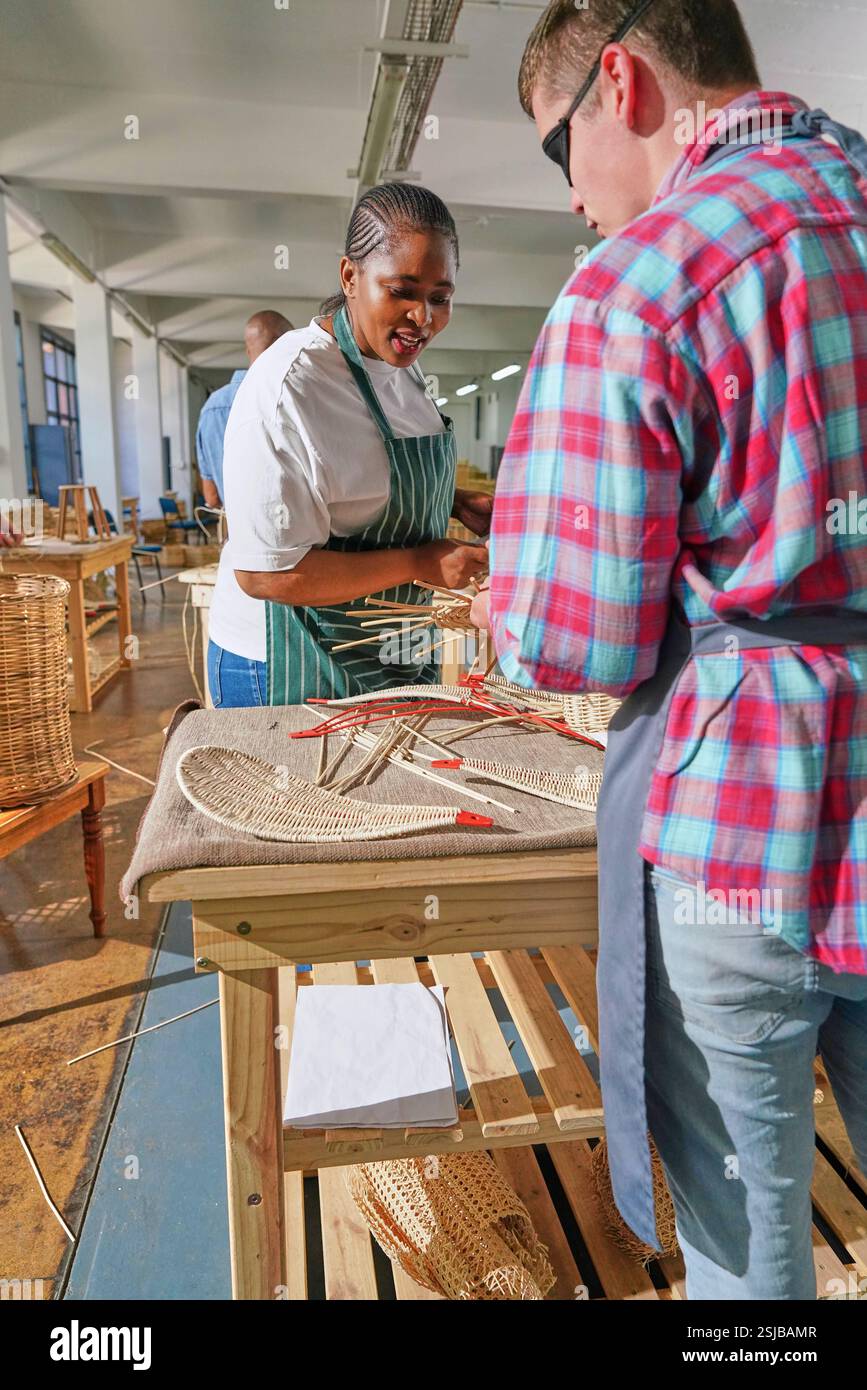Deux artisans fabriquant des meubles tissés en atelier Banque D'Images