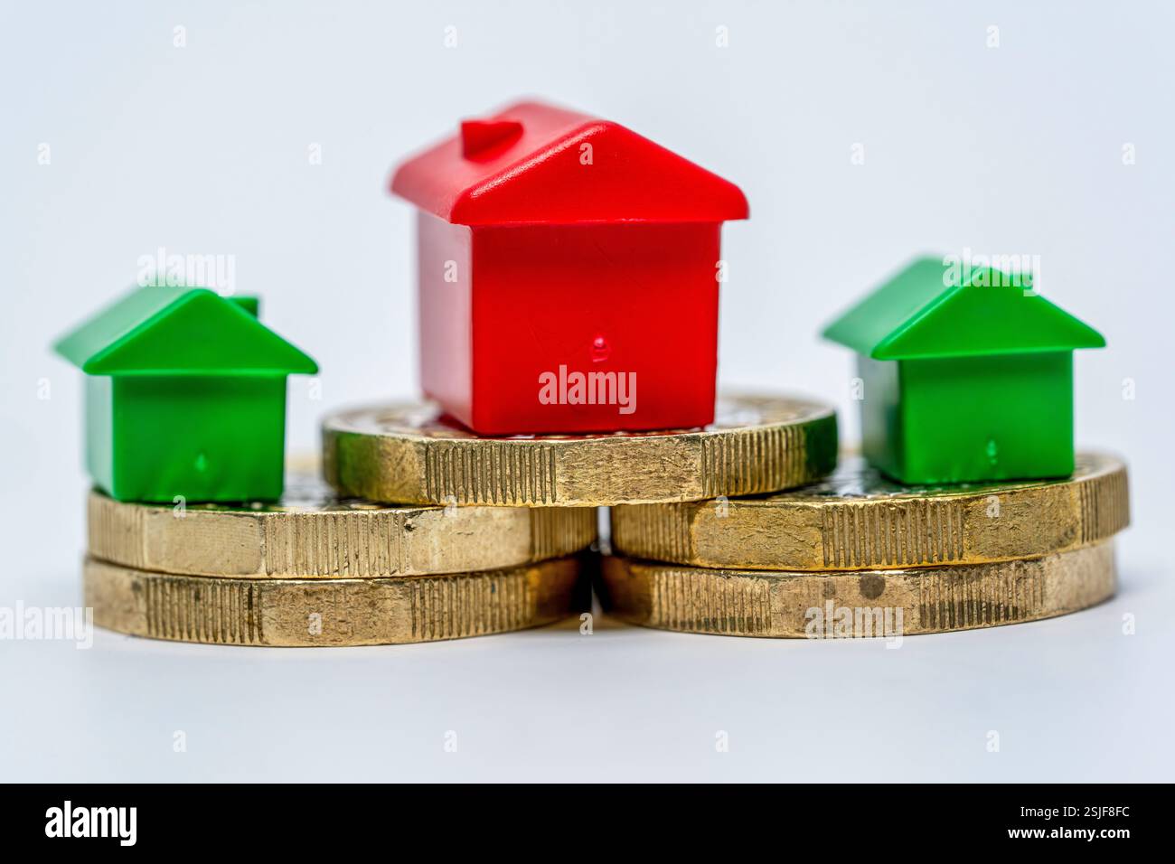 Représentation symbolique de l'investissement immobilier avec des maisons en plastique et des pièces empilées Banque D'Images