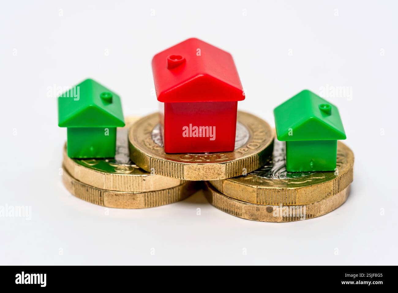 Représentation symbolique de l'investissement immobilier avec des maisons en plastique et des pièces empilées Banque D'Images