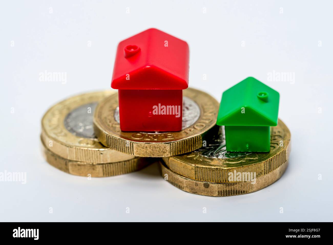 Représentation symbolique de l'investissement immobilier avec des maisons en plastique et des pièces empilées Banque D'Images