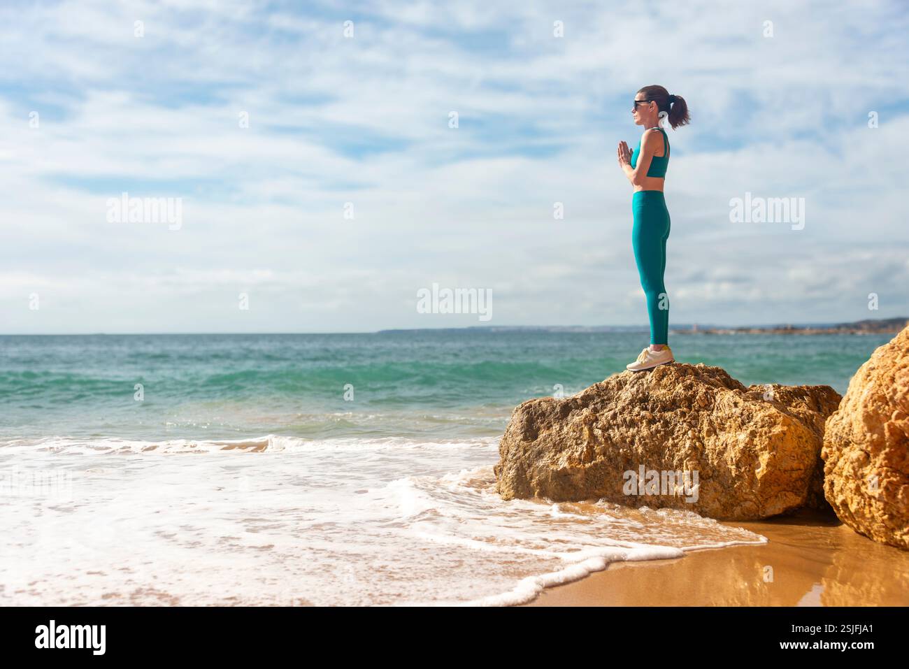 femme sportive debout sur un rocher au bord de la mer méditant et pratiquant le yoga Banque D'Images femme sportive debout sur un rocher au bord de la mer méditant et pratiquant le yoga Banque D'Images