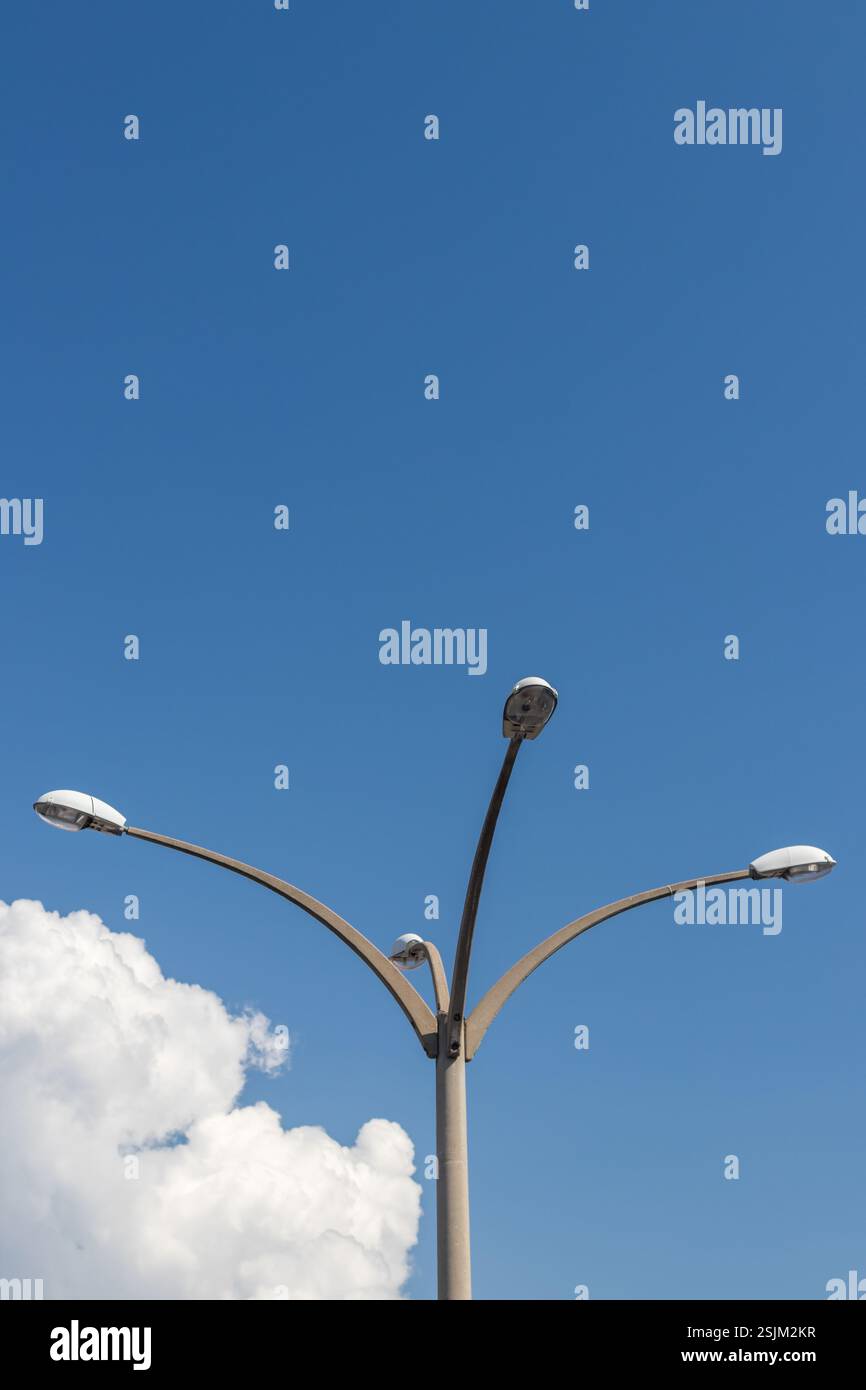 Scène extérieure mettant en vedette un lampadaire moderne debout haut sous un ciel bleu clair avec des nuages. Banque D'Images