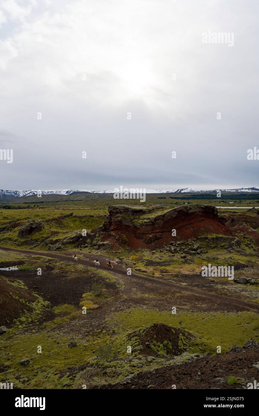 Trois cavaliers traversent un paysage de montagne volcanique en Islande Banque D'Images