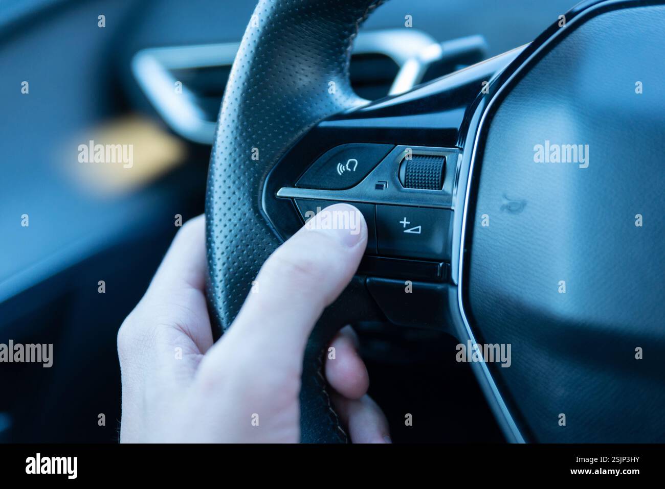 Gros plan d'une main appuyant sur le bouton de commande vocale sur un volant, présentant la technologie de voiture intelligente, l'assistance pilotée par IA et le système mains libres Drivin Banque D'Images