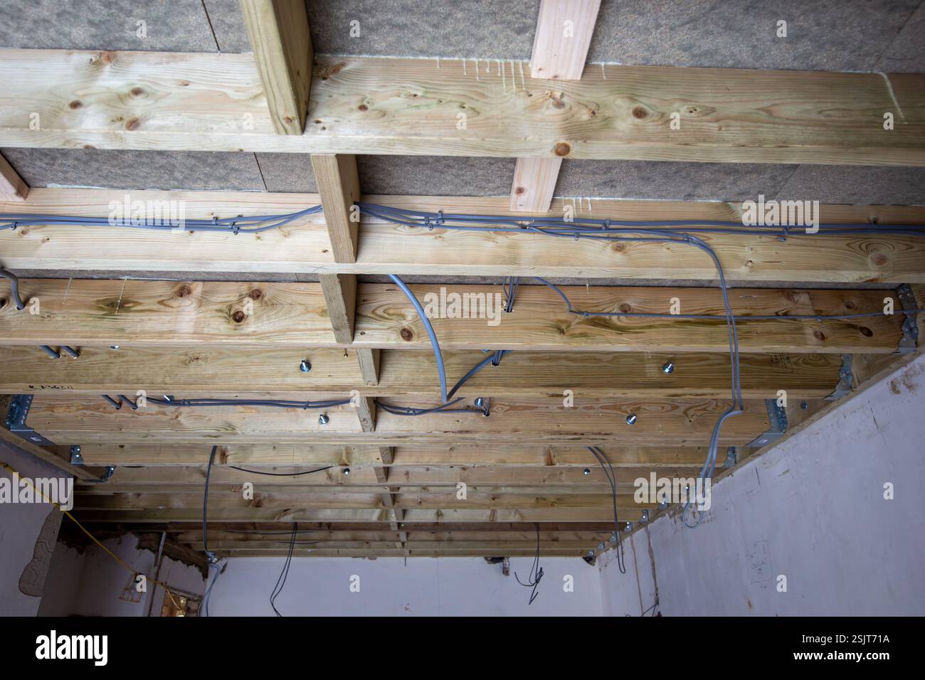 Vue d'un plafond non fini avec poutres apparentes et fils électriques dans un intérieur de chantier de construction Banque D'Images