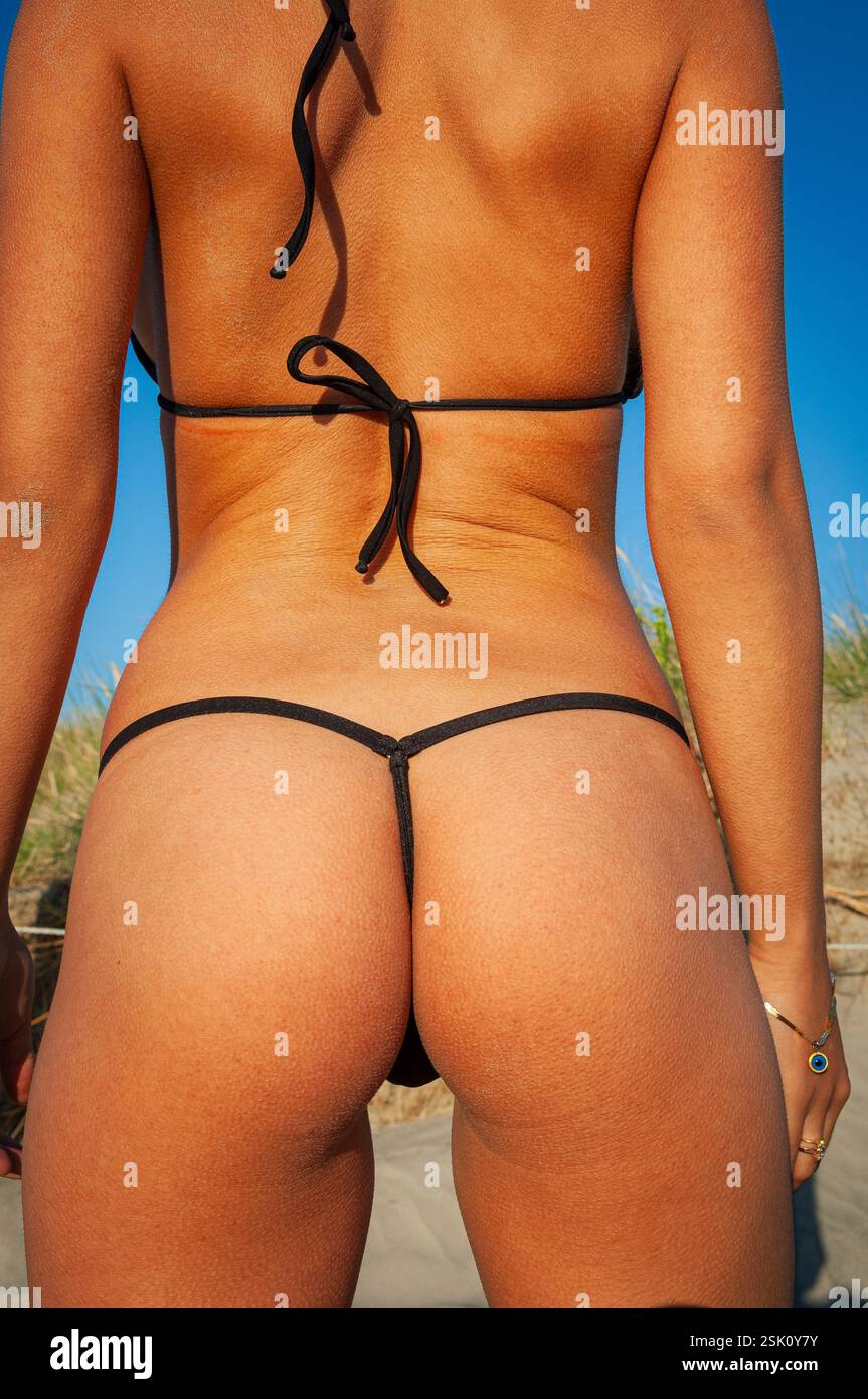 Vue arrière d'une jeune femme mince et bronzée des années 20 portant un bikini à ficelle noire Banque D'Images