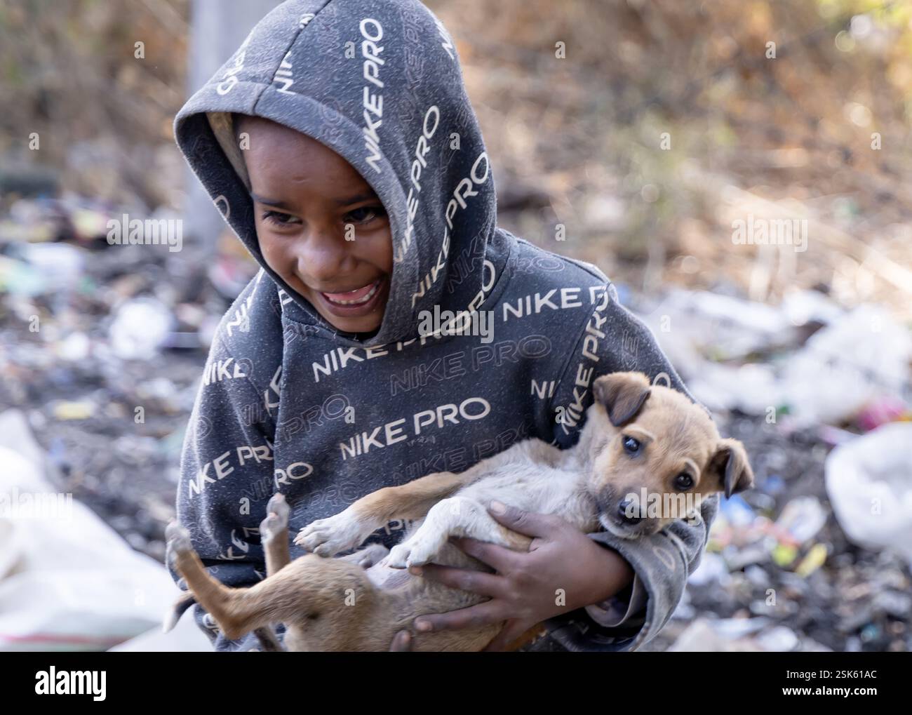 innocent pauvre gosse collecteur d'ordures avec sourire mignon et chien en main à l'extérieur le jour Banque D'Images