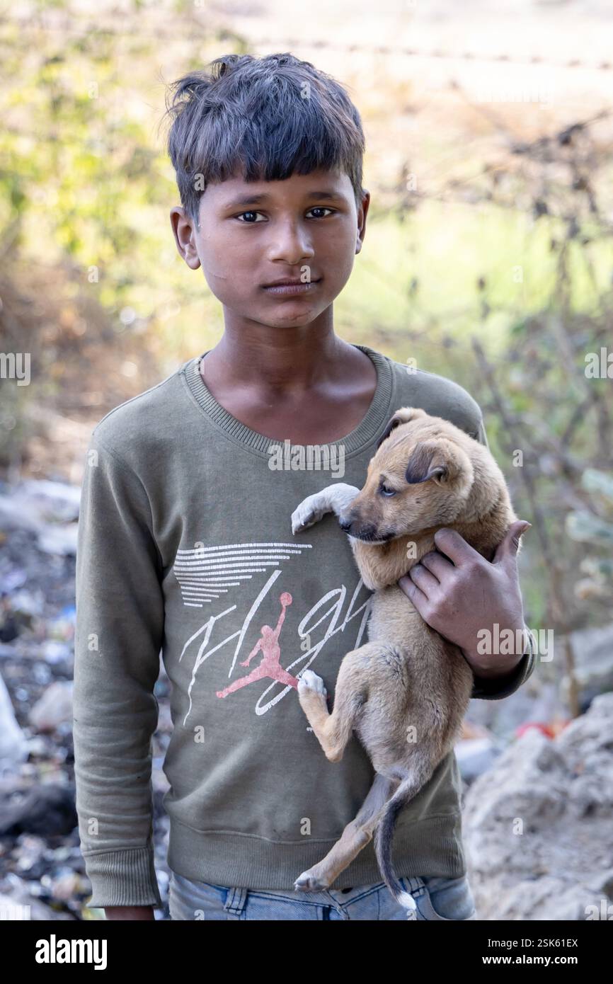 innocent pauvre garçon collecteur d'ordures tenant le chien chiot en main à l'extérieur le jour Banque D'Images