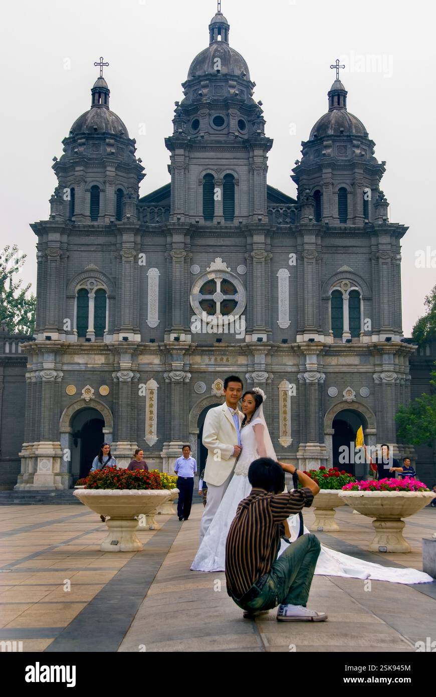 Pékin, CHINE- jeune couple chinois nouvellement marié posant pour un photographe devant l'église catholique sur la rue Wangfujing. Taux de mariage en Chine Banque D'Images