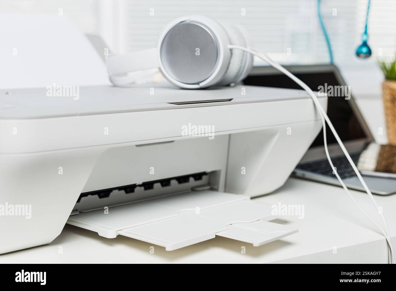 Configuration de bureau moderne avec une imprimante, des écouteurs et un ordinateur portable sur un bureau bien rangé pendant la journée Banque D'Images